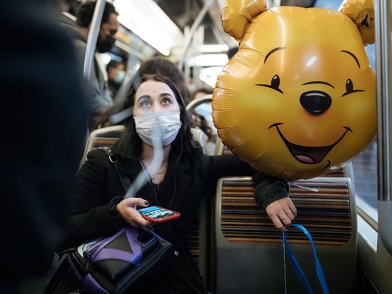 A masked woman holds a Winnie the Pooh inflatable balloon inside the Paris subway on Thursday, Oct. 29, 2020.. Image Credit: AP